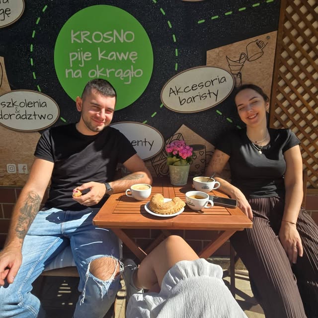 Stolik na zewnątrz lokalu z muralem Krosno pije kawę na okrągło